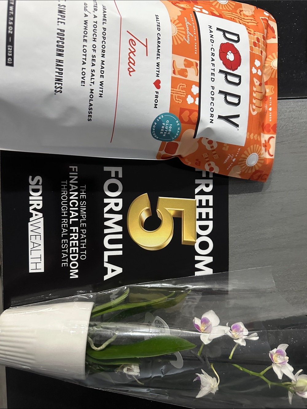 Gift of - White Mini Orchid in Clear Sleeve with Orange Popcorn Bag & book